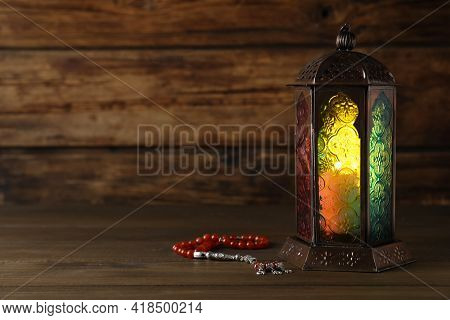 Decorative Arabic Lantern And Misbaha On Wooden Table. Space For Text