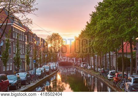 Delt canal with old houses and cars parked along on sunset