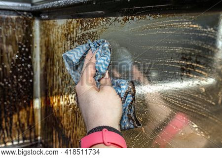 A Woman Washes With A Kitchen Cloth The Corner Pane Covered With Soot Of A Modern Fireplace With A C