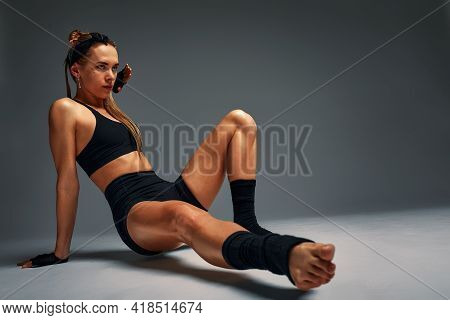 Beautiful And Athletic Girl In A Top And Shorts And Black Socks Posing In Studia On A Gray Backgroun