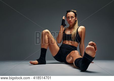 Beautiful And Athletic Girl In A Top And Shorts And Black Socks Posing In Studia On A Gray Backgroun