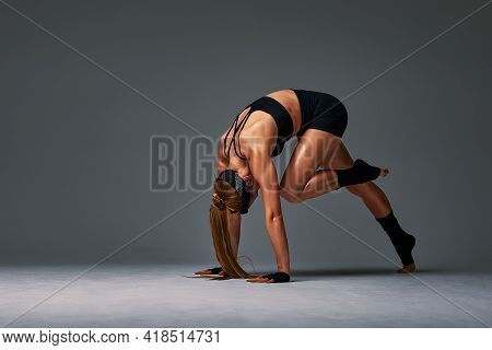 Beautiful And Athletic Girl In A Top And Shorts And Black Socks Posing In Studia On A Gray Backgroun