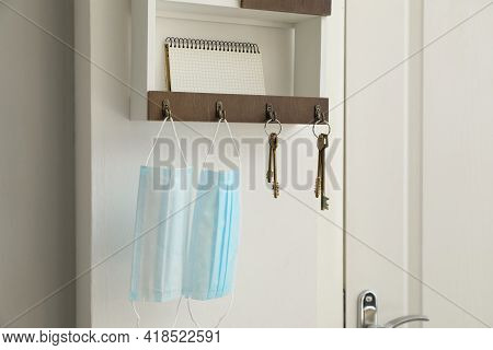 Hanger For Keys With Protective Masks And Notebook On Shelf Near Door In Hallway
