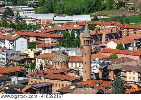 View from above of houses with red roofs and belfry of Madonna della Moretta church in town of Alba, Piedmont, Northern Italy.