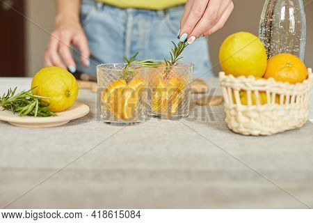 Female Hand Put Rosemary In Glasses, Making Fresh Lemonade