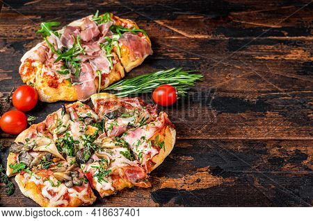 Sliced Pizza With Prosciutto Parma Ham, Arugula And Parmesan Cheese. Dark Wooden Background. Top Vie