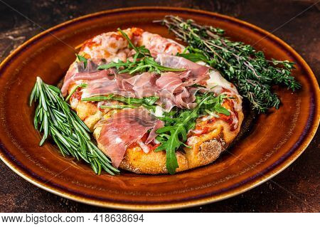 Pizza With Prosciutto Parma Ham, Arugula Salad And Parmesan Cheese In A Rustic Plate. Wooden Backgro