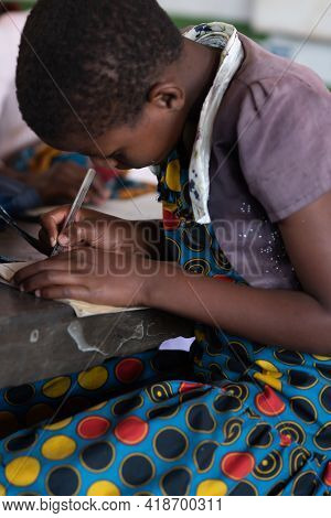 Mzuzu, Malawi. 30-05-2018. Beautiful Portrait Of A Afro Girl Sitting At Her Bench Writing On Her Not