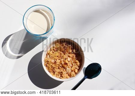 Bowl Of Cereal And Glass Of Milk On White Background. Healthy Breakfast With Cornflakes And Milk. To