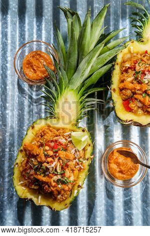 Thai Cashew Chicken Fried Rice Served In A Pineapple Bowl With Sriracha And Peanut Satay Sauce