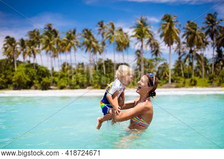 Mother And Baby On Tropical Beach With Coconut Palm Trees. Mom And Little Boy Swimming And Playing I