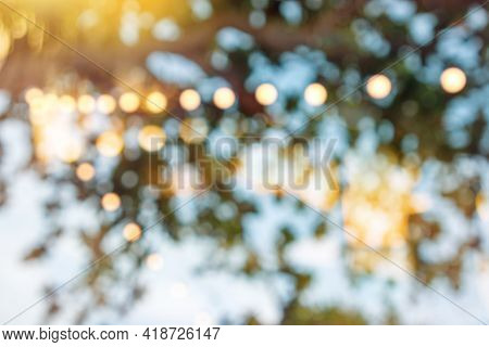 Blurred Bokeh Light On Sunset With Yellow String Lights Decor In Beach Restaurant, Tranquility Of Se