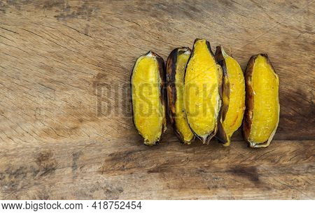 Grilled Silver Bluggoe Banana Or Kluai Hak Mook On Old Wooden Background. Delicious Golden Brown Gri