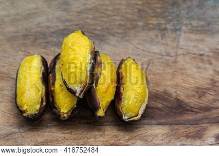 Grilled Silver Bluggoe Banana Or Kluai Hak Mook On Old Wooden Background. Delicious Golden Brown Gri