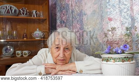 Elderly Lonely Woman Depressed Sitting At The Table