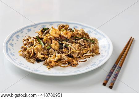 Serving Of Simple Penang Char Kuey Teow Is Popular Fried Noodle With Coceral, Shrimp And Eggs In Bla