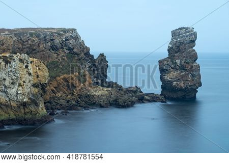Long Exposure Seascape Of The Cliffs Of Papoa Island In Carvoeiro Cape From The Sea At Sunrise In A 