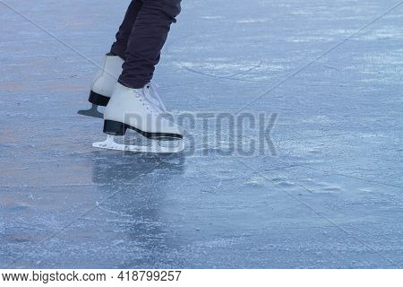 A Child In White Skates Clumsily Rides In Winter On The Ice Of A River Or Lake