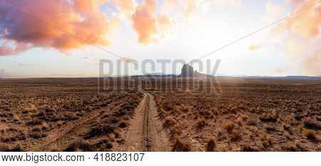 Striking Panoramic Landscape View Of A Dirt Road In The Dry Desert With A Mountain Peak In The Backg