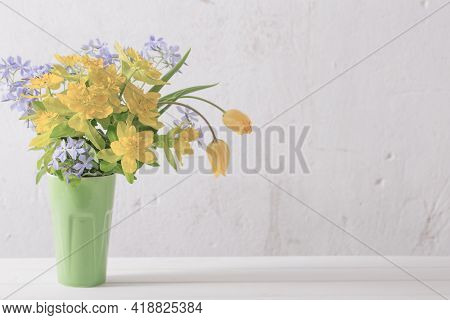 Yellow And Blue Flowers In Vase On Background Old White Wall