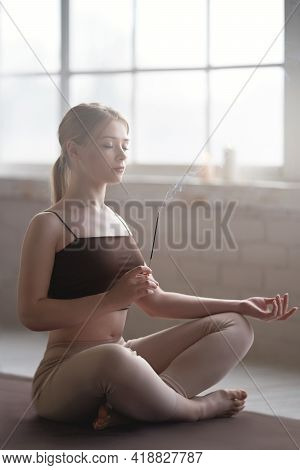 Beautiful Young Woman Meditating With Scent Stick. Morning Airy Enlightened Mood. Camera Focus On Sm