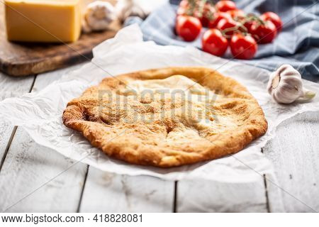 Traditional Hungarian Dish Langos Served On A Baking Paper In The Background With Garlic Tomatoes An