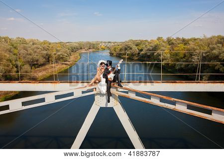 Bride And Groom On The Bridge Over The River
