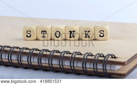 Wooden Blocks With The Word Stonks On Wooden Notebook. Business And Finance Concept.