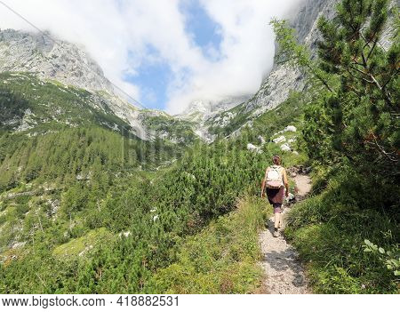 Young Woman Walks In A Trail While Hiking In The Mountains Between The Alps And The Mountain Pines