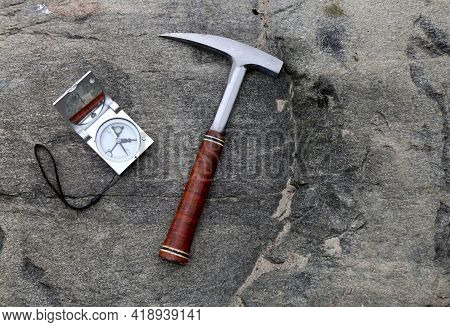 Geologists Compass On The Stones With Hammer. Geology Science Concept. The Geologists Hammer And Too