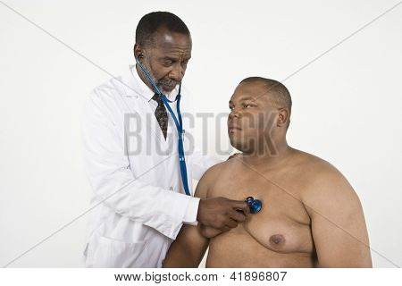 An African American doctor checking blood pressure of a patient in clinic