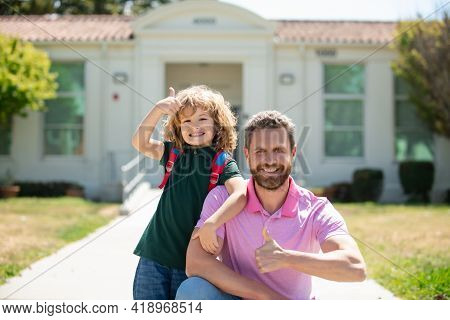 Portrait Of Parent And Pupil With Thumbs Up Of Primary School Go Hand In Hand. Teacher In T-shirt An