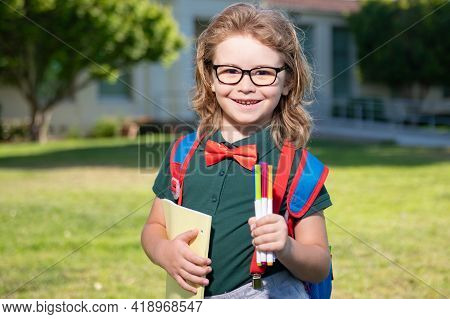 Smiling School Student Wit Backpack Book. Portrait Of Happy Pupil Outside The Primary School. Closeu