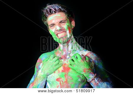 Portrait of a man bares his teeth all in paint in the studio