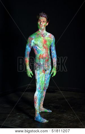 Naked man covered in paint in the studio