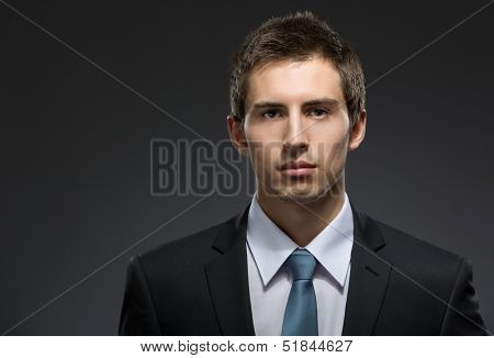Front view of self-confident business man in dark suit with black tie. Concept of professionalism and success in business