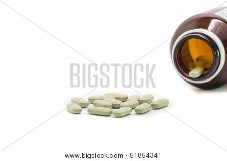 Prescription pill bottle spilling pills on to surface isolated on a white background