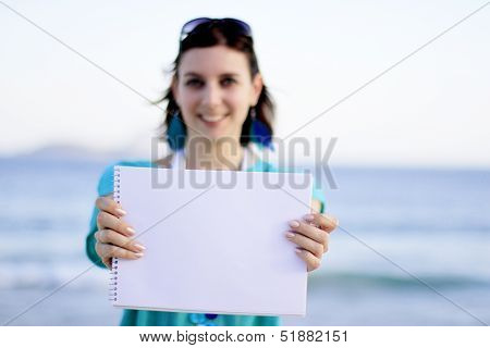 woman holding a paper at the beach