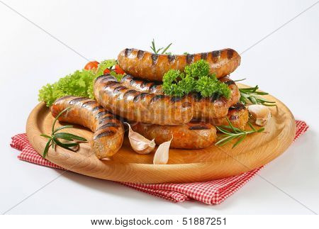 grilled bratwurst with salad and garlic, served on a wooden cutting board