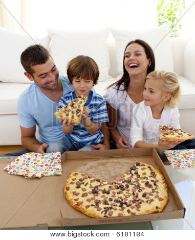 Eltern und Kinder essen Pizza im Wohnzimmer