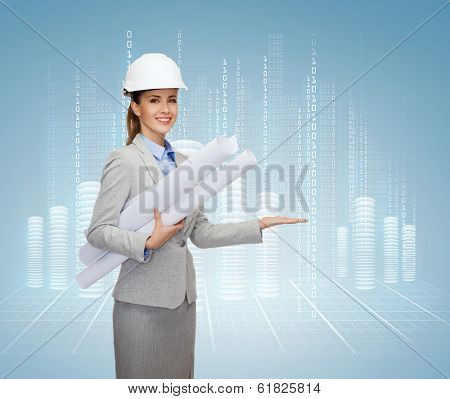 building, developing, consrtuction and architecture concept - smiling architect in helmet with blueprints showing something on palm of hand