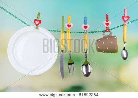 Tableware dried on rope on natural background