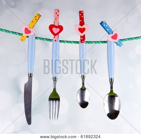 Cutlery dried on rope on bright background