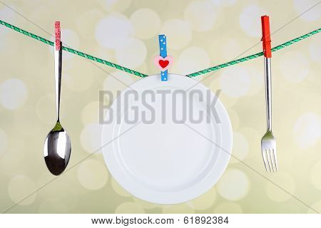 Tableware dried on rope on bright background