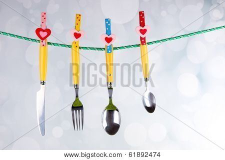 Cutlery dried on rope on bright background