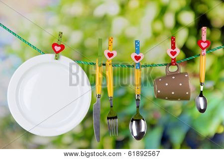 Tableware dried on rope on natural background