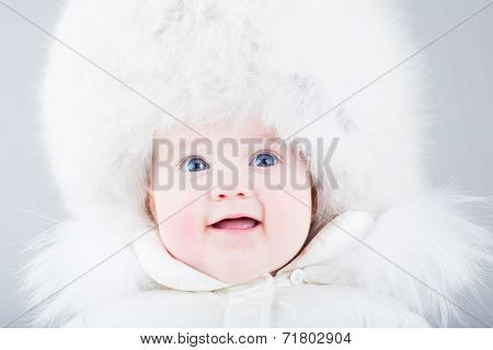 Happy Laughing Baby In A Big Fur Hat And White Snow Jacket