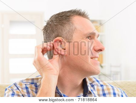 Man showing deaf aid in ear