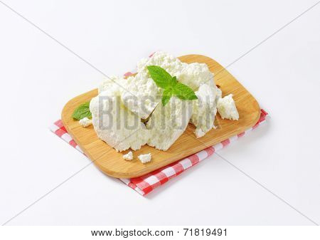 slices of fresh cheese on wooden cutting board and checkered dishtowel