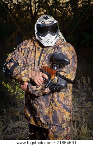 Paintball player posing with a gun in the middle of the playing field.